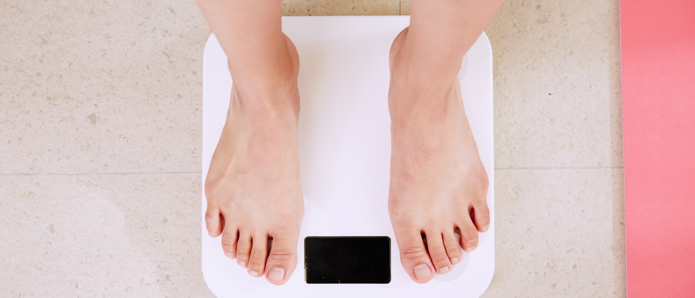 Person stepping onto a white digital bathroom scale